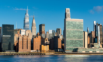 Naklejka premium Midtown East Manhattan skyline across the East River in New York City. Cityscape of modern skyscrapers, landmarks and office buildings in morning light
