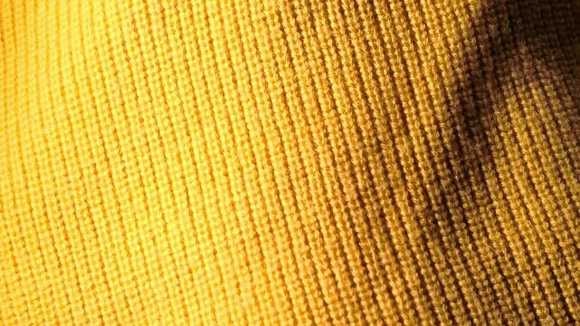 Yellow knitted fabric texture macro background showing textile weave detail and cozy material surface.