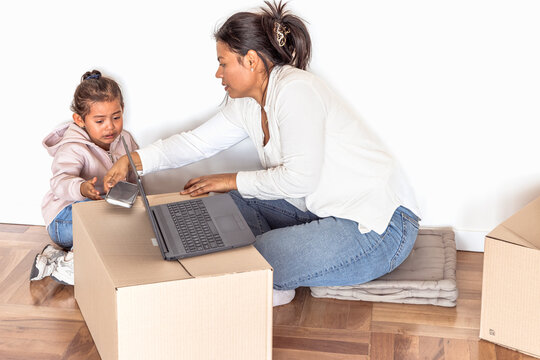 Stressed mother working at new home giving child cell phone after managing screen time conflict
