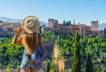 Fototapeta premium Woman tourist with backpack looking at Alhambra fortress in Granada, Spain. travel in Europe