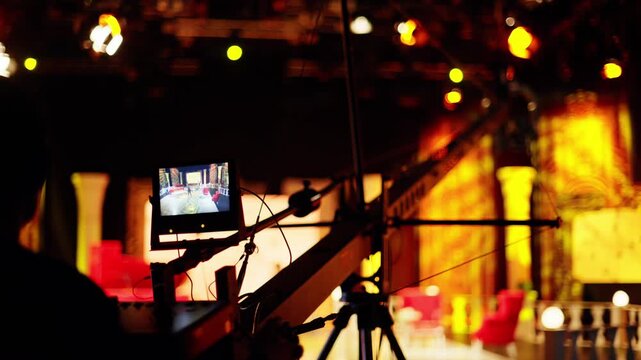 Professional cameraman operating crane camera during live television broadcast in bright studio.
