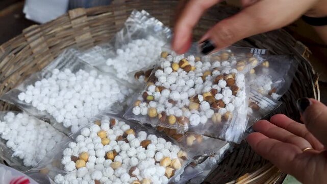 Close up video footage of hands holding packed prasad snacks and religious food offerings for Hindu worship rituals at temple in Uttarakhand India.