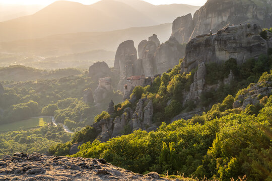 Amazing panoramic view of the Meteora valley with the monasteries in the golden hour of the sunset against the background of the setting sun, near Kastraki, Greece.