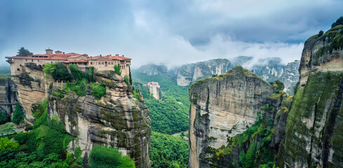 Fototapeta premium Amazing panoramic view with the majestic Varlaam Monastery amid creeping mists in the Meteora Valley near Kastraki, Greece