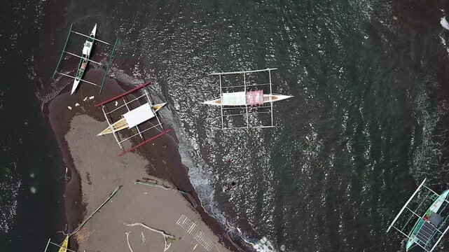 Small fishing boats are brought ashore for safety due to rising waves from the approaching typhoon threatening a small fishing village.  Drone aerial
