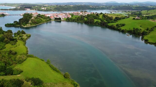Wide aerial panoramic view of San Vicente de la Barquera estuary and coastline, featuring the green landscape, historic town and the Atlantic Ocean in Cantabria, Spain. High quality 4k footage