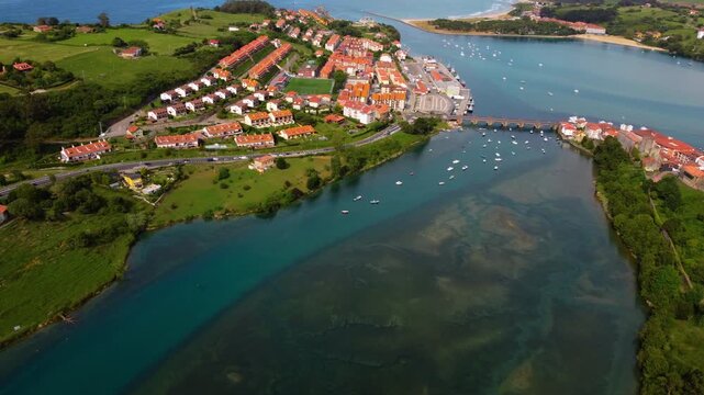 Wide aerial panoramic view of San Vicente de la Barquera estuary and coastline, featuring the green landscape, historic town and the Atlantic Ocean in Cantabria, Spain. High quality 4k footage