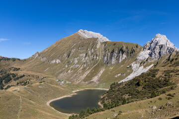 Fototapeta premium Panoramic alpine scene of Lessy lake with rocky peaks and serene natural surroundings in the Bornes massif, Haute-Savoie
