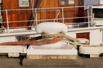 Obraz premium Thick mooring ropes and a red hose secured to a white bollard on the wharf in Auckland, New Zealand for a ship.