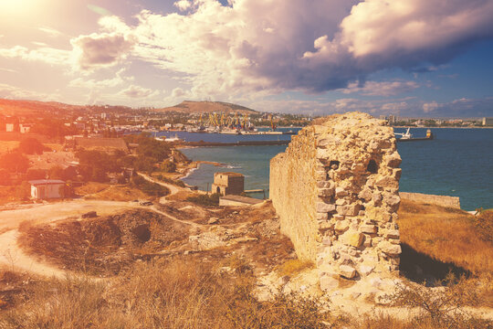 Ruins of the Genoese fortress of Caffa (Feodosia) Crimea. Rocky seashore. Sea nature landscape. View of the sea and Feodosia city from the mount. Port, harbor.