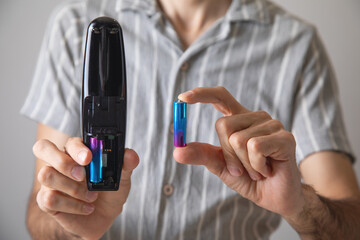 Man installs a new battery in the remote control of a TV.