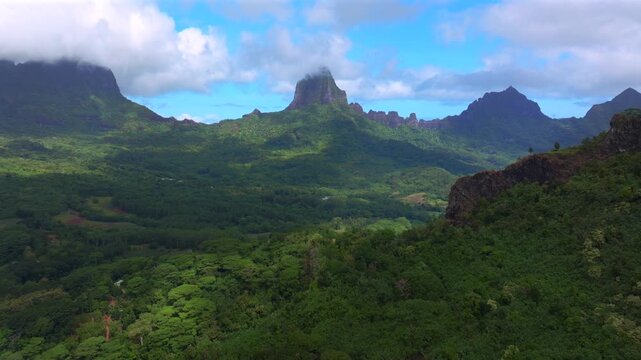 Dramatic volcanic jagged peaks rugged terrain Mount Rotui Mt Toheia Moorea French Polynesia aerial drone Belvedere Lookout landscape Cooks Opunohu Bay sunny morning blue sky low clouds circle left