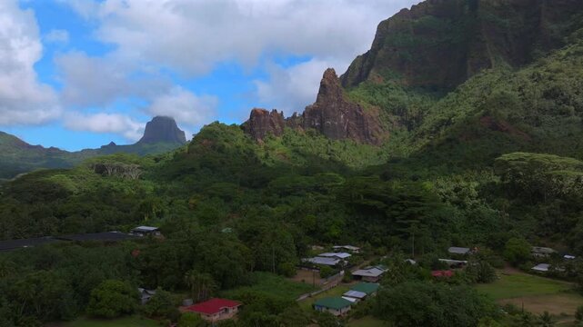 Cooks Opunohu Bay beach homes Mount Rotui Mt Toheia Dramatic volcanic tall jagged peaks rugged terrain Moorea French Polynesia aerial drone Belvedere Lookout sunny morning blue sky clouds forward