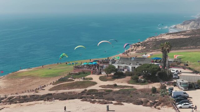 Paragliders flying over ocean bluffs near Torrey Pines San Diego aerial captured with smooth cinematic drone footage