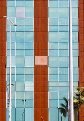 Obraz premium Front view of a modern building facade featuring a grid pattern of blue glass windows combined with vertical brown wooden composite cladding panels.