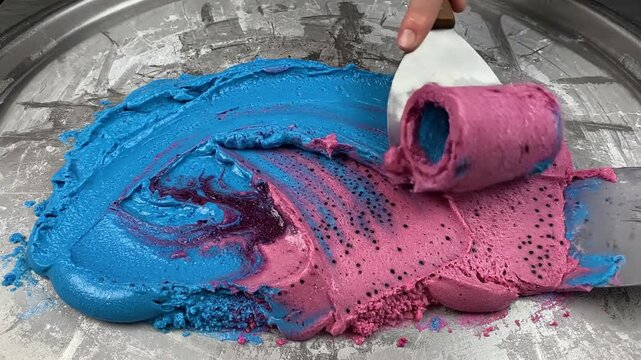 Vibrant blue and pink ice cream being rolled into sorbet
