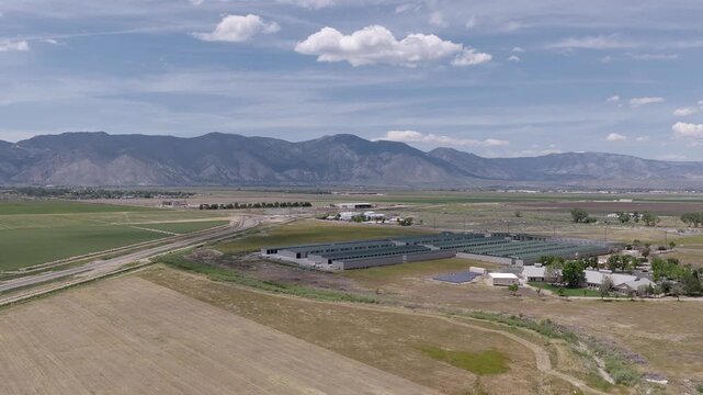 Stunning aerial footage showcasing the sprawling agricultural fields and modern farm buildings near Minden, Nevada, with the majestic Sierra Nevada mountain range creating a dramatic backdrop