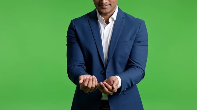 Businessman in dark suit and tie standing confidently with hands clasped in front of green background
