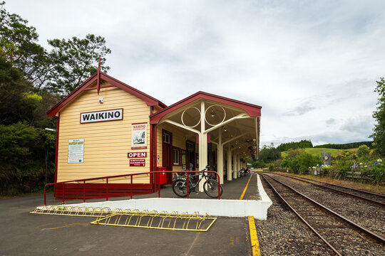 The cream‑and‑red Waikino railway station caf&eacute; stands beside the tracks, with bicycles parked out front and hills rising in the background