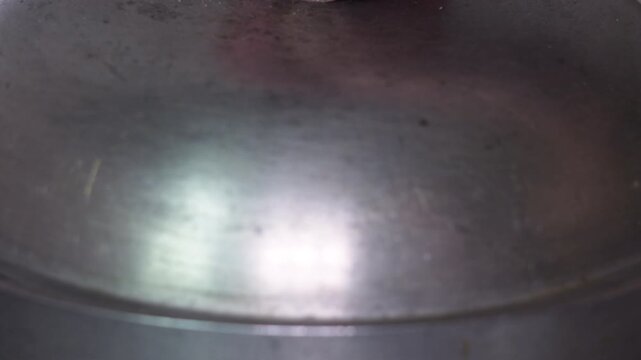 Close-up view of homemade dumplings boiling in a metal pot with water, cooking traditional dough-based food at home.