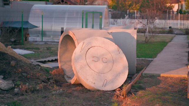 Concrete well rings with cover lying in backyard for septic tank installation