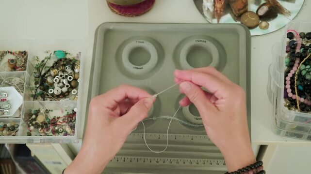 Close-up of hands of a woman artisan creating natural stone bracelets