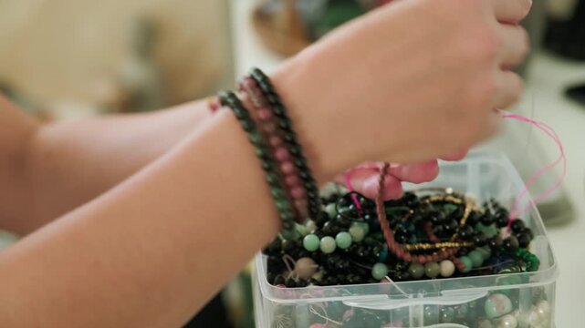 Close-up of hands of a woman artisan creating natural stone bracelets