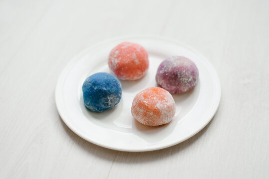 Four Different Colorful Mochi Rice Cakes Served on White Round Plate