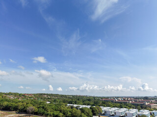 Obraz premium Wide aerial view of luxury hotel resorts, holiday villas, and dense green canopy under a vast blue sky at Geger Beach, Bali, Indonesia