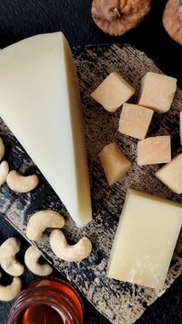Aged cheese in a triangular block with jam, figs, and nuts. Aged cheese as a food background for your design