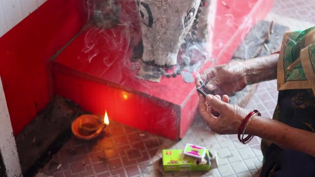 Raw video footage of burning dhoop sticks releasing smoke during a Hindu temple ritual in rural Uttarakhand, India. Spiritual devotion and peaceful religious atmosphere.