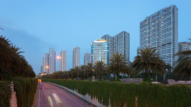 Blue hour timelapse of the Trung Hoa underpass in Hanoi with light trails, palm-lined roads, and modern residential towers.