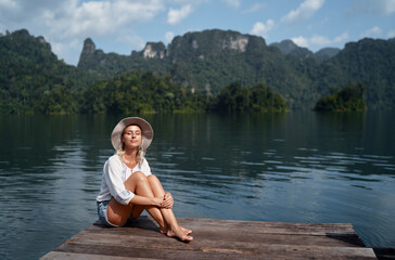 Fototapeta premium Tranquil Woman Relaxing by a Serene Lake in Natural Surroundings