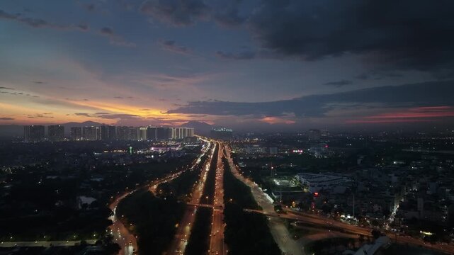 Aerial twilight view of Thang Long Boulevard in Hanoi with illuminated traffic lanes stretching toward the horizon beneath a dramatic sunset sky.