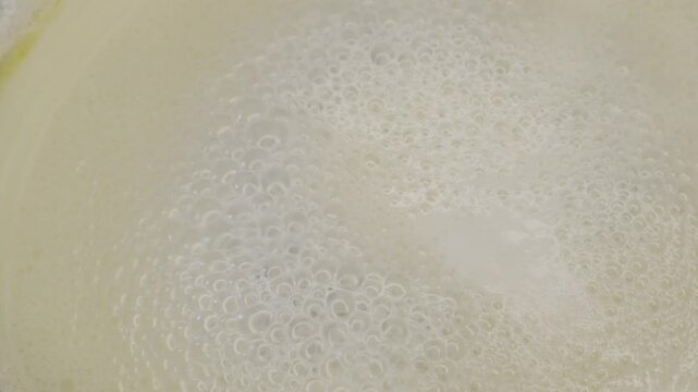 Close-up top view of boiling fresh cow milk in a stainless steel pot with foam texture and showing natural dairy preparation in a warm kitchen atmosphere in India.