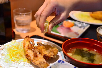 Squeezing lime over the fried puffer fish lunch set at Japanese restaurant  © Vassire