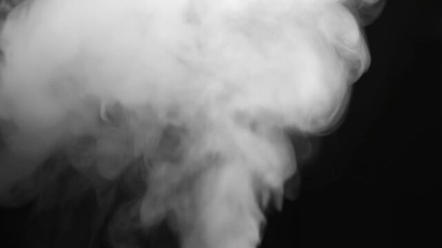 Dramatic white smoke rising against black background in slow motion