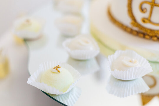 Elegant wedding petit fours and white confections displayed on a mirrored tray with gold monogram cake