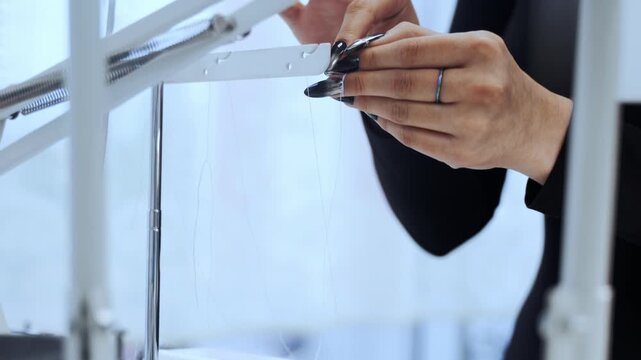 Woman's hands placing a spool of thread on a sewing machine, preparing for needlework