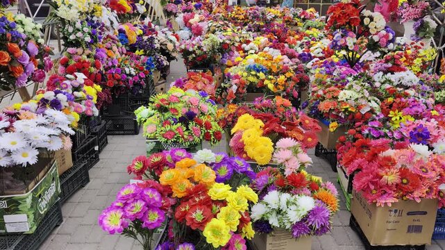 Extensive collection faux flowers showcased retail environment, diverse color palette, numerous types of blossoms, variety shapes and sizes, eye-catching visual presentation, commercial floral sale po