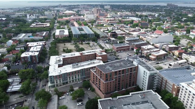 Historic core sweep captures Meeting St, downtown midrise buildings transitioning into church steeples, brick structures, dense residential blocks extending toward Cooper River in Charleston, SC