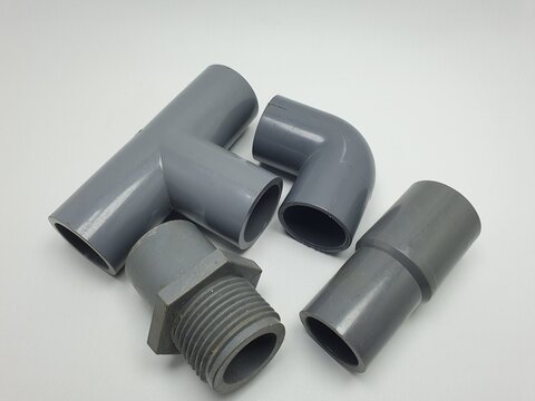 PVC pipe fittings collection: tee, elbow, and threaded adapters. High-quality grey plastic plumbing connectors isolated on white background. Essential industrial hardware components.