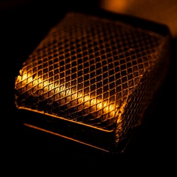Extreme macro shot of the fine metal mesh of a Faraday cage enclosure on a pure black background.