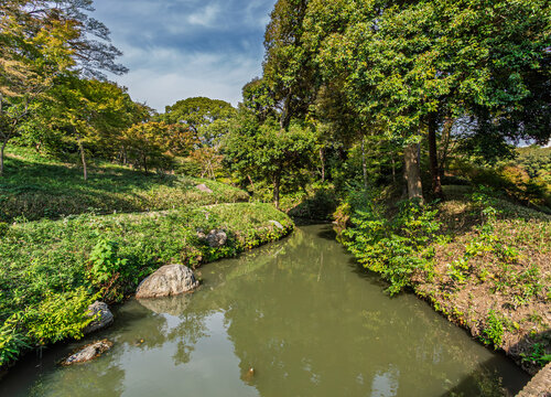 A peaceful stream flowing through the lush green woods at Rikugien Garden Tokyo November 2023