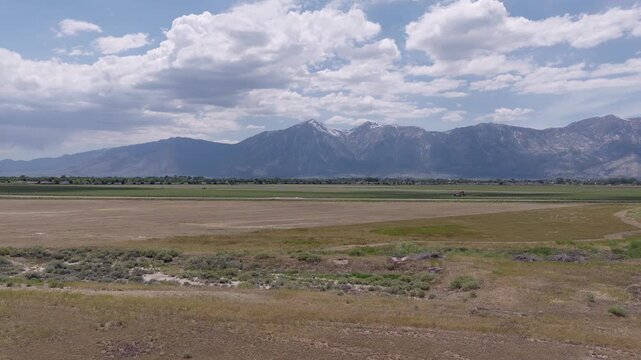 Ascending drone view of the agricultural fields and valley floor near Minden, Nevada, showing the beautiful landscape with the majestic Sierra Nevada mountains rising in the distance