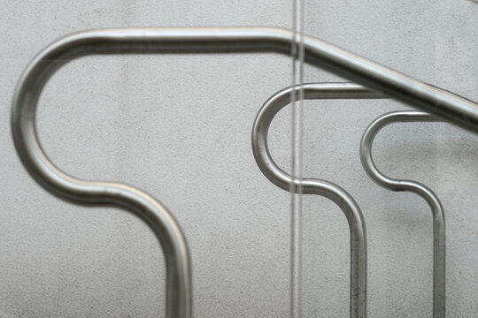 Curved metal handrails trace across concrete wall in a black and white photograph, turning stair detail into minimal urban architecture