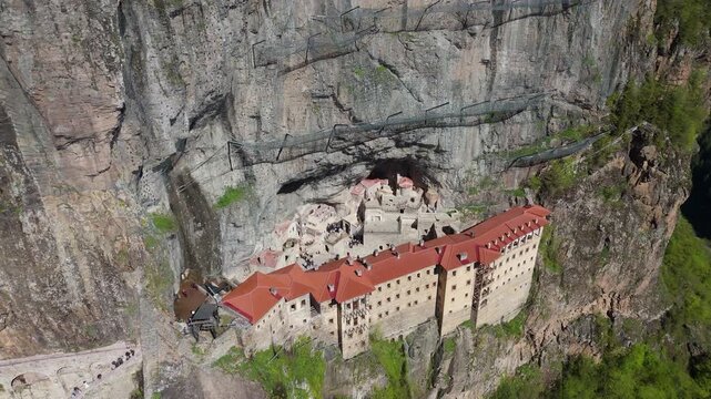 top-down drone perspective of the historic Greek Orthodox Sumela Monastery nestled among dense green pine woods in Trabzon, Turkey travel destination