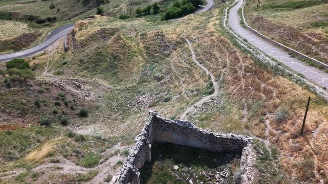 Cinematic 4K drone slow flyover of ancient ruined caravanserai. Detailed stone architecture, historical atmosphere, travel and archaeology cinematic footage.