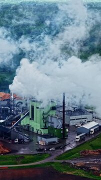 Vertical drone view of Stora Enso sawmill facility releasing thick white steam from chimneys in Launkalne, Latvia