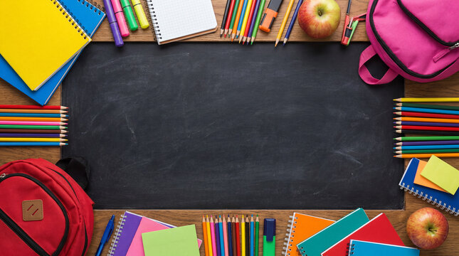 School supplies framing a blank blackboard with books, pencils, and backpacks for education concept